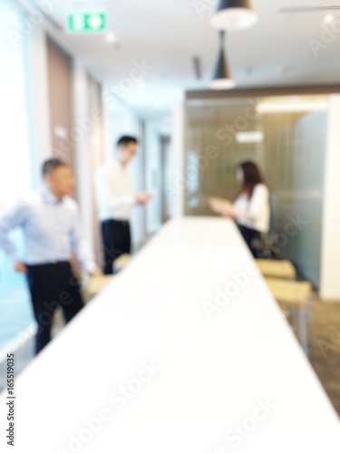 blurred image of Three young coworkers working together in a modern office. two  businessman  looking at the businesswoman and laughing.Woman discussing with colleague new project in business lounge