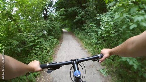 A man on a bicycle rides fast on a dirt road in the forest. Action camera go pro.