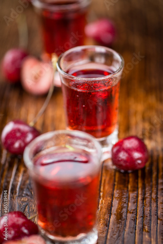 Cherry Liqueur on wooden background; selective focus