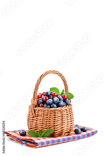 Basket with blueberries and red currants isolated on white background.