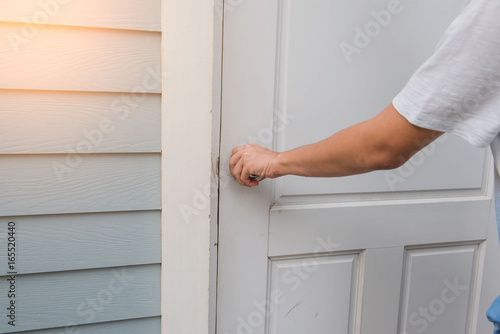 hand open the white door knob or opening the door.