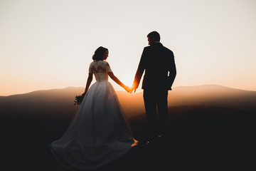 Wedding couple posing on sunset at wedding day. Bride and groom in love
