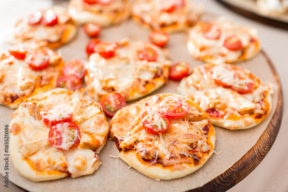a lot of mini pizza, on wood plate. catering buffet. soft focus a lot of mini pizza, on wood plate. catering buffet. soft focus
