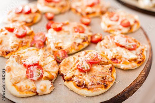 a lot of mini pizza, on wood plate. catering buffet. soft focus