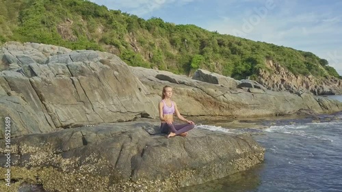 Flycam Removes from Girl Relaxing in Yoga Pose against Hill photo