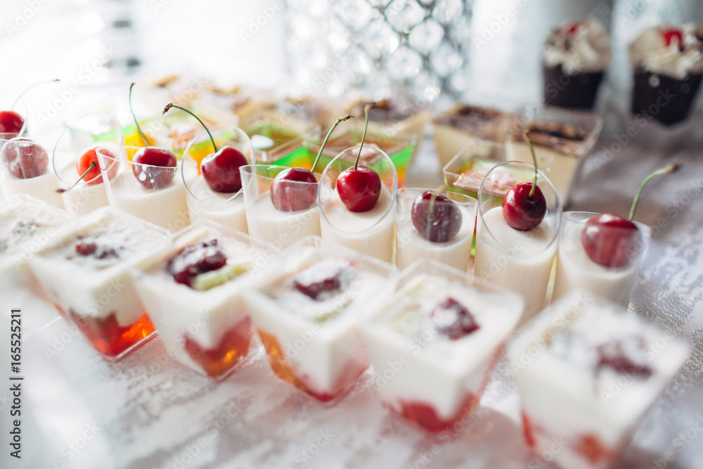 The cup of jellies  with cherries stand on the banquet table