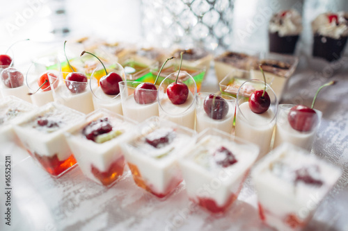 The cup of jellies with cherries stand on the banquet table