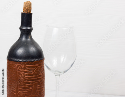 Black bottle of wine and wneglass on the wooden background photo