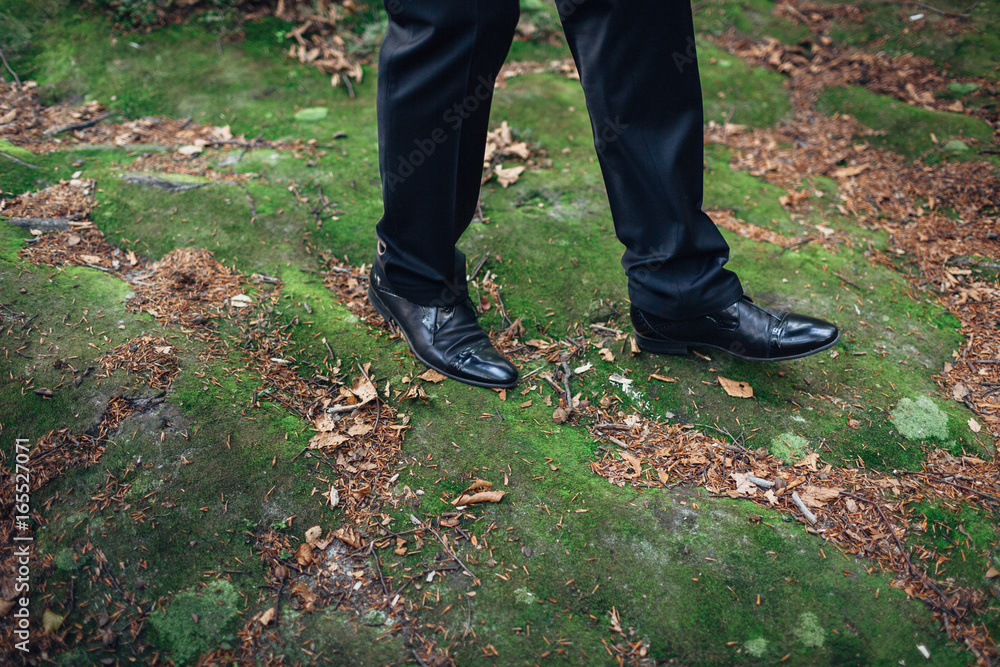 Groom in elegant suit walks in the forest Groom in elegant suit walks in the forest