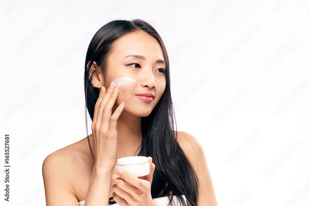 Beautiful young woman on white isolated background applies cosmetic face cream, asian Beautiful young woman on white isolated background applies cosmetic face cream, asian