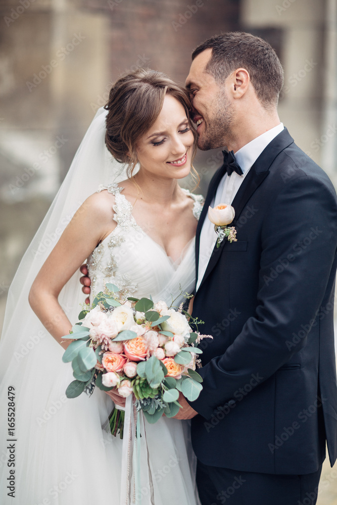 Classy wedding couple poses on the old European street Classy wedding couple poses on the old European street