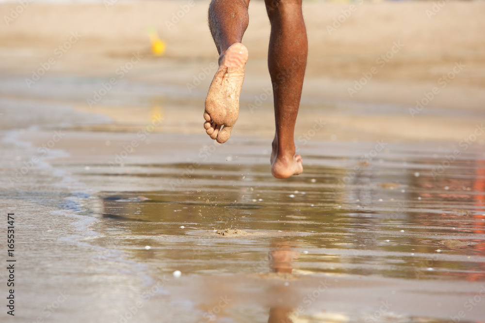 Man running barefoot along beach