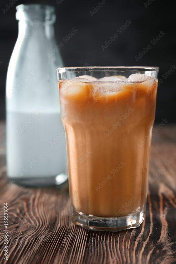 Glass with cold brew coffee and bottle of milk on wooden table Glass with cold brew coffee and bottle of milk on wooden table