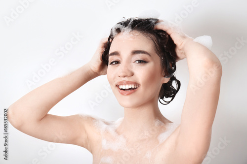 Young woman washing hair wh...