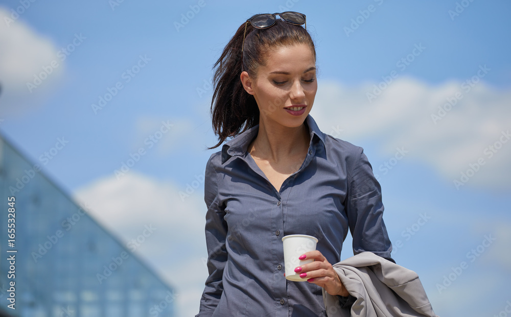 Beautiful young businesswoman with a disposable coffee cup, drinking coffee, against urban city background. Beautiful young businesswoman with a disposable coffee cup, drinking coffee, against urban city background.