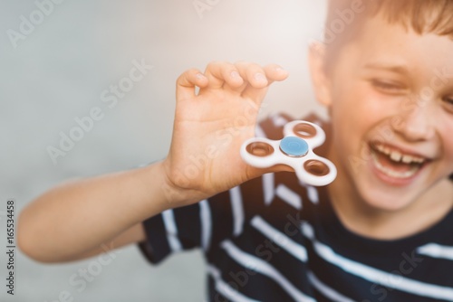 Little child boy playing with fidget spinner outdoors photo