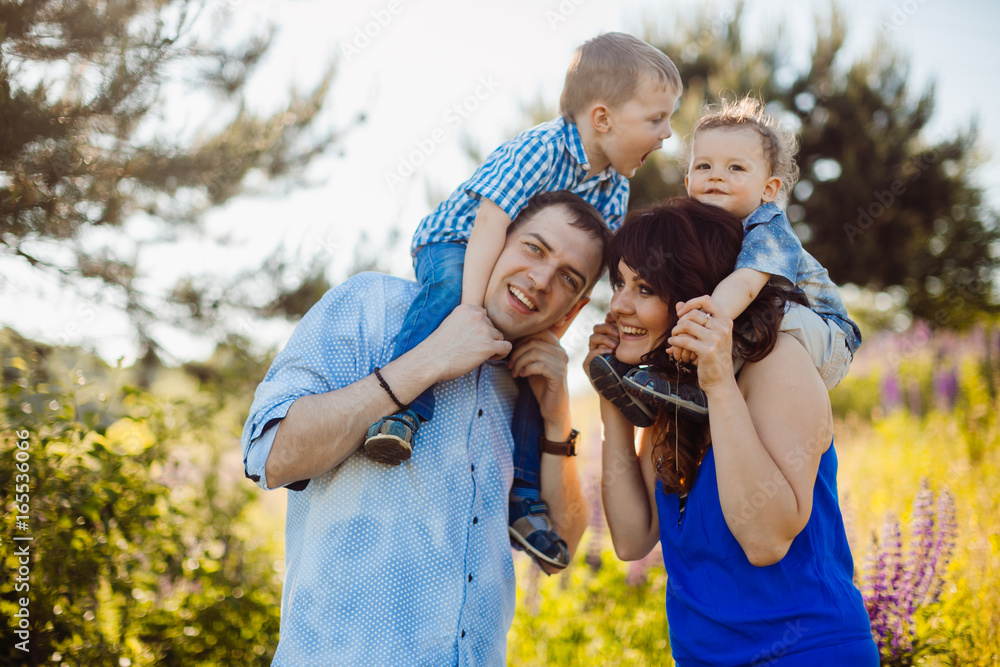 Parents hold their little sons on the shoulders standing on the field of lavander Parents hold their little sons on the shoulders standing on the field of lavander