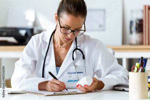 Beautiful female pharmacist holding jar of pills in hands. photo