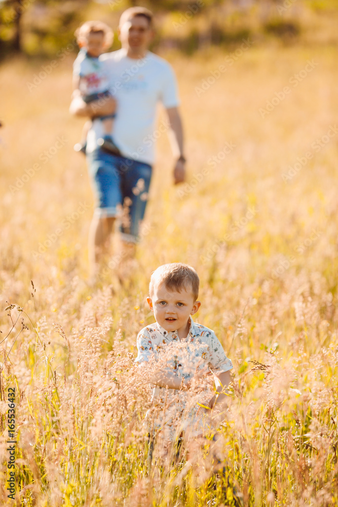 Fototapeta premium Parents walks with their children on sunny field