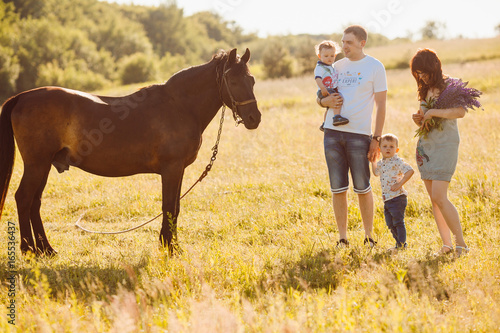 Family with children stand before a brown horse