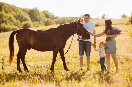 Family with children stand before a brown horse © pyrozenko13