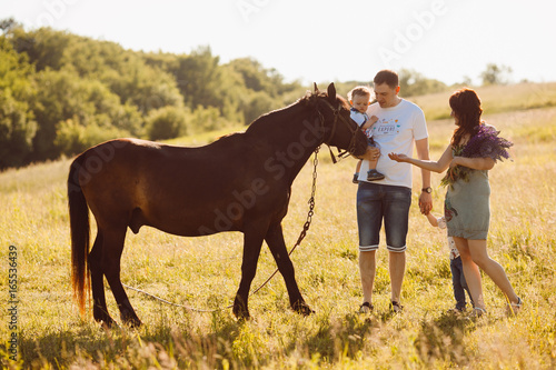 Family with children stand before a brown horse