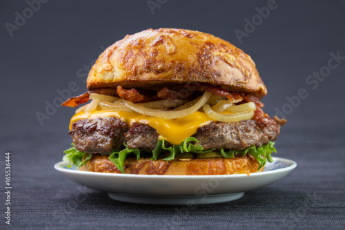 Cheeseburger with bacon and cooked onion on plate , with toasted cheese bun