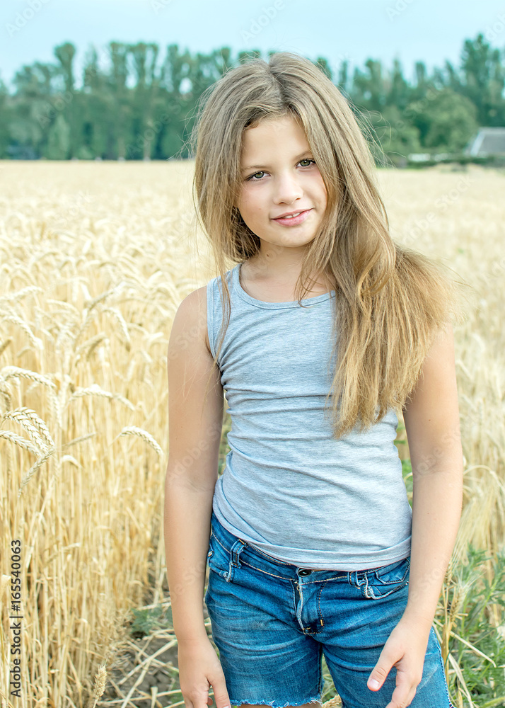 adorable little girl with long heir Posing in golden wheat field at a summer day adorable little girl with long heir Posing in golden wheat field at a summer day