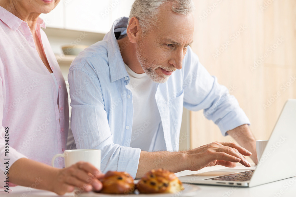 Cheerful mature loving couple family using laptop computer Cheerful mature loving couple family using laptop computer