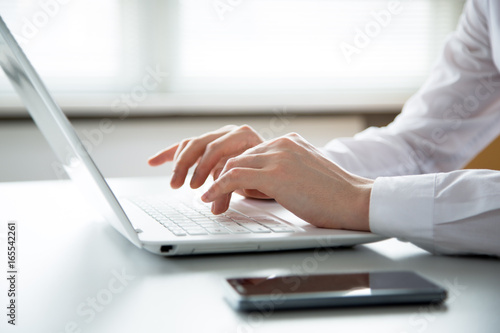 Close-up of hands of business man typing on a laptop. © chagin
