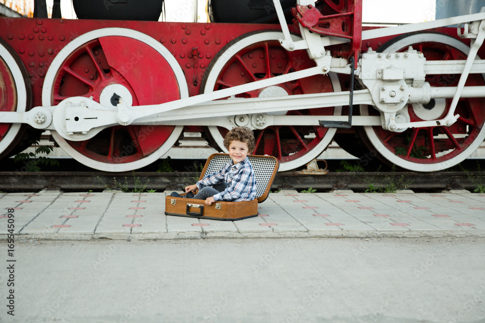 Naklejka premium Smiling boy sitting in open suitcase
