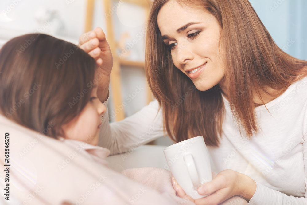 Pretty woman touching forehead of her daughter Pretty woman touching forehead of her daughter