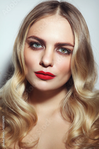 Young beautiful woman with red lipstick and blonde curly hair