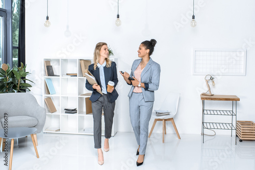multicultural businesswomen having conversation while walking in office