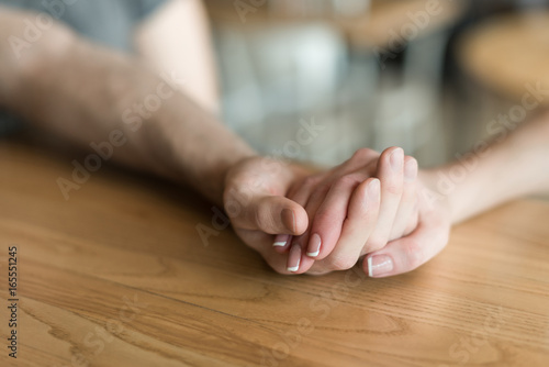 partial view of couple holding hands while sitting in cafe together © LIGHTFIELD STUDIOS