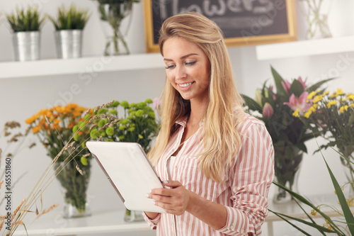 Female florist working in flower shop with tablet