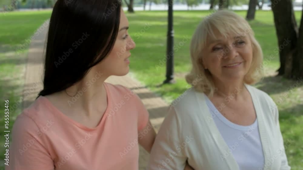 Pleasant woman and her senior mother walking in the park Pleasant woman and her senior mother walking in the park
