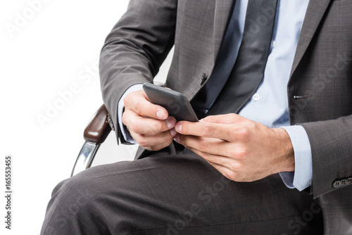 cropped shot of businessman using smartphone while sitting on chair isolated on white