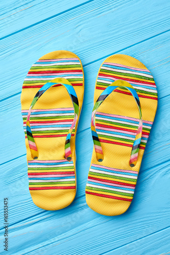 Summer fashion striped sandals. Colorful flip flops on blue background.