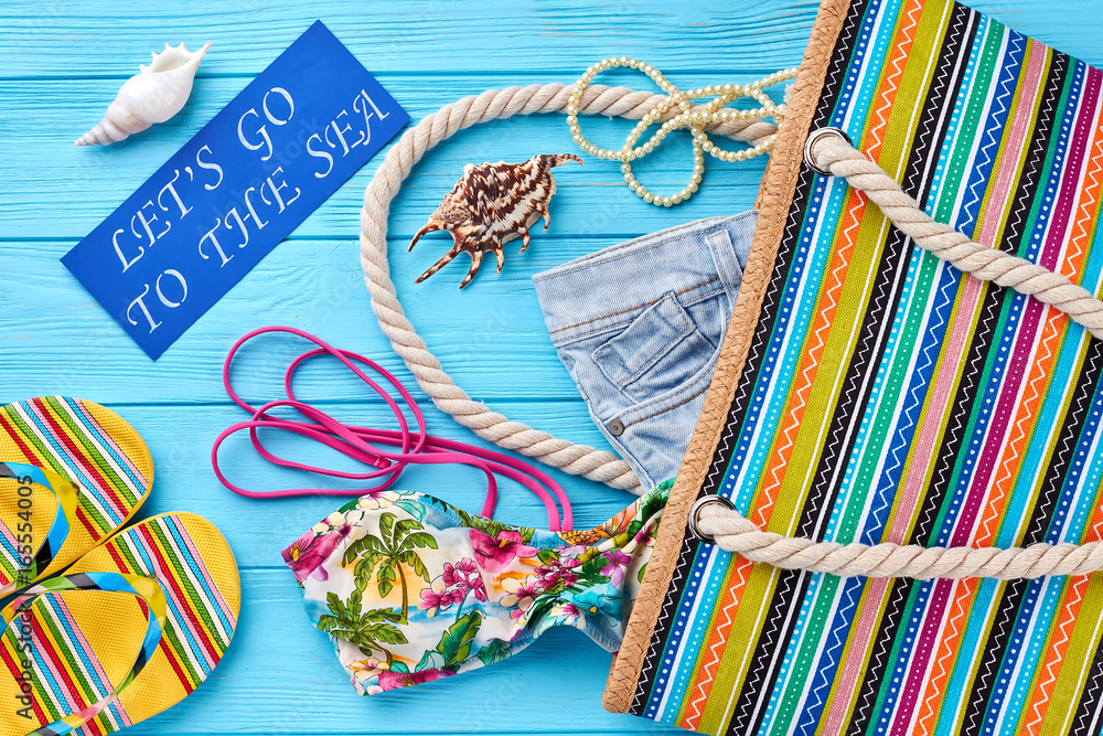Naklejka premium Bright image of summer fashion set. Striped female handbag, sandals, bra, denim shorts, necklace, message.