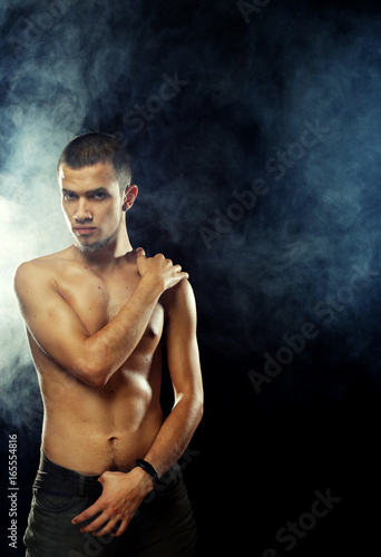 Portrait of a muscular male model against dark  background with  © Raisa Kanareva