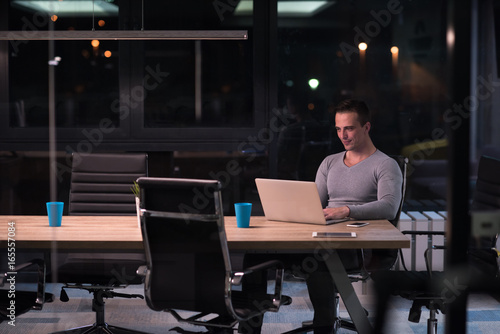man working on laptop in dark office