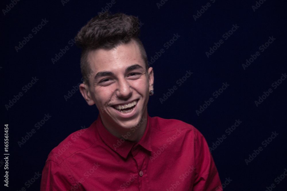 one teenager boy, red shirt, Caucasian, dark background, looking to camera, laughing
