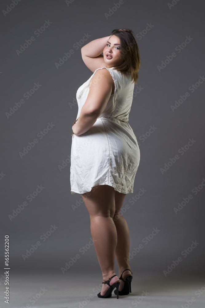 Foto de Happy plus size model in casual clothes, fat woman on gray