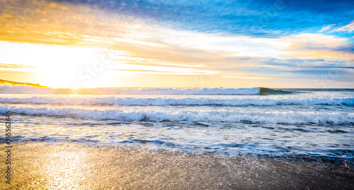 Small ocean sea waves on sandy beach with sunrise sunset.