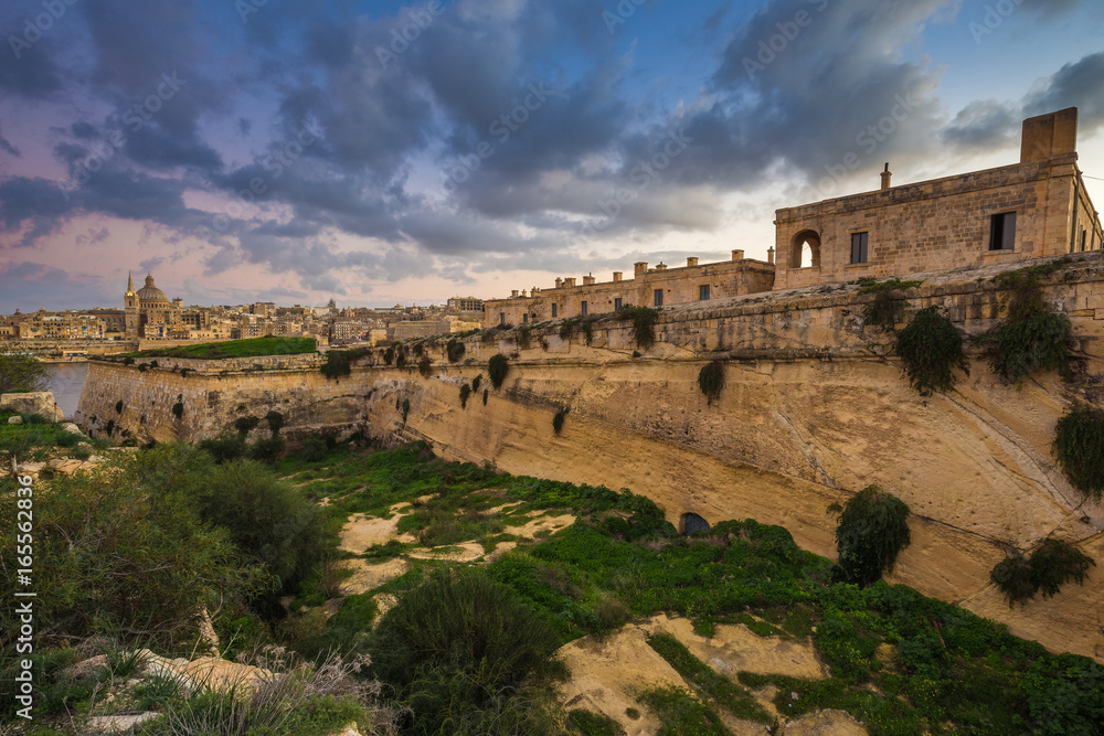Manoel Island, Malta - Abandoned limestone fortress at the center of Manoel Island with Saint Paul's Cathedral and Valletta at the background