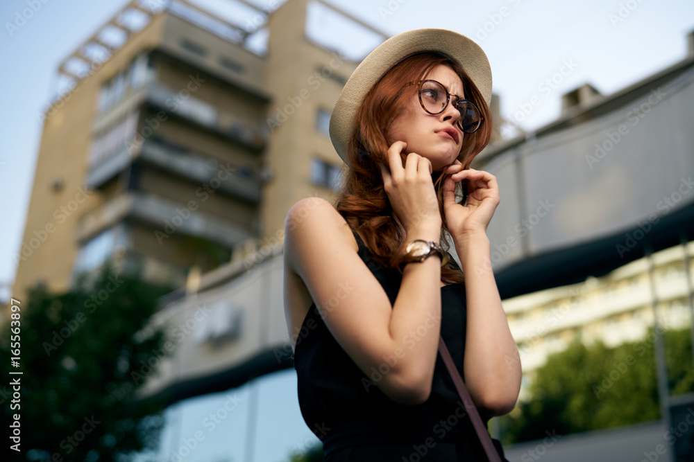 Fototapeta premium Beautiful young woman is walking along the street in the city in summer