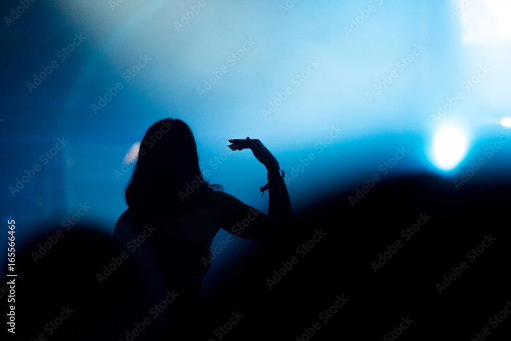 Silhouette of concert crowd in front of bright stage lights