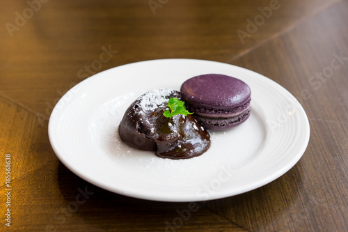 Chocolate lava cake with macaroon and peppermint on white plate  selective focus
