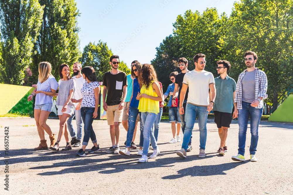 Large group of friends walking together at park Large group of friends walking together at park